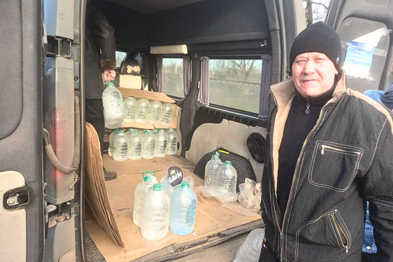 Story 1 (Vitaly Ivanov) Ukrainian man standing next to back of the van with water bottles